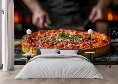 Closeup of a deep dish pizza with a blurred background of a person cutting it. Wall mural