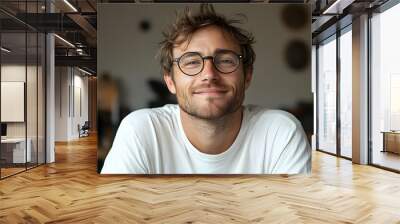 Portrait of a smiling man with a beard wearing round glasses. Wall mural