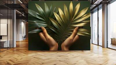 Two hands holding a golden and green palm leaf against a green background. Wall mural