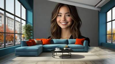 Young woman with brown hair smiling in a black blazer. Wall mural