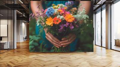 A close-up of a hand holding a beautiful bouquet of wildflowers. Wall mural