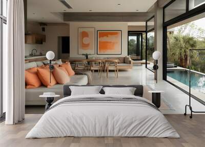 A modern living room with a large window overlooking a swimming pool and lush tropical greenery. The room features a white sofa with orange pillows, a rug, and two abstract paintings on the wall. Wall mural