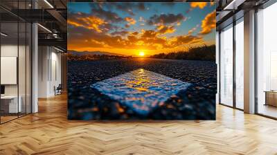 A scenic sunset view along a road with vibrant clouds and a marked lane. Wall mural