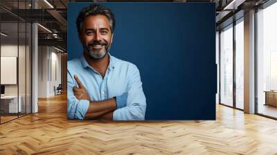 A smiling man in a casual shirt poses confidently against a blue background. Wall mural