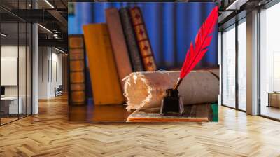 Red quill pen, black inkwell and a rolled papyrus sheet on an old book with a blue background Wall mural