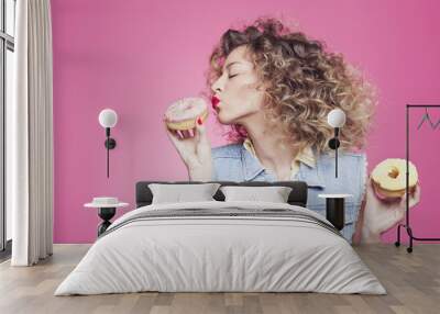 girl kissing a doughnut on a pink background Wall mural