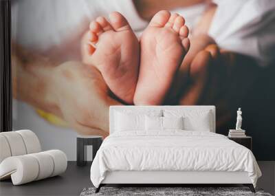 small feet of a newborn supported by the hand of his father Wall mural