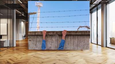 Escape from jail. Prison wall with barbed wire and a watchtower on blue sky background. Wall mural