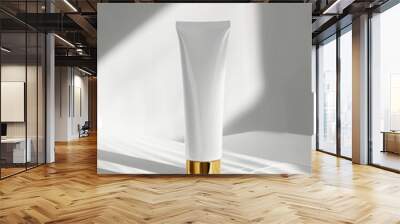 The elegant white plastic tube with golden cap, standing upright on a white surface with soft light shadows, beauty product concept Wall mural