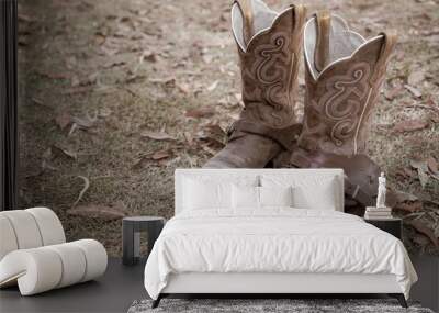 pair of dirty old cowboy boots with spur straps on a background of dry grass and leaves. Wall mural