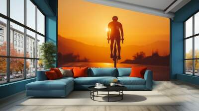 Rear back view of a cyclist man silhouetted against the orange twilight sky, riding on an asphalt road at dusk. Highlights summer outdoor sport activity and healthy lifestyle. Wall mural