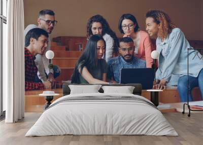 Group of students is using laptop sitting in classroom and talking, young people are working at project. Modern lifestyle, higher education and modern technology concept. Wall mural