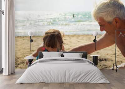 Caucasian grandfather and granddaughter playing together on the beach. Wall mural