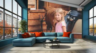 Young blond Caucasian caressing little brown pony Wall mural