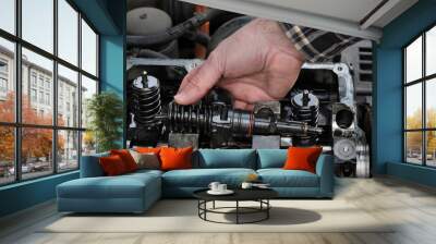 Car mechanic fixing modern diesel engine, closeup of hand holding injector with cylinder head and engine in background Wall mural