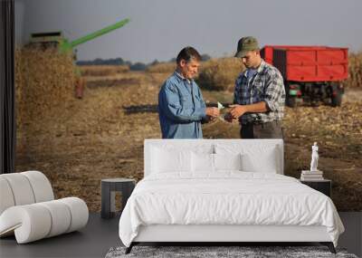 Farmer and buyer  holding Euro banknote with corn field with tractor and combine in background Wall mural