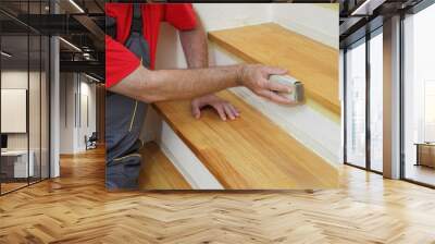 Worker sanding plank at stairs using sand paper, home renovation Wall mural