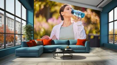 Fitness, woman and water for hydration in yoga for healthy, exercise or workout in the nature outdoors. Female drinking from bottle holding mat for exercising, training and wellness in health sport Wall mural