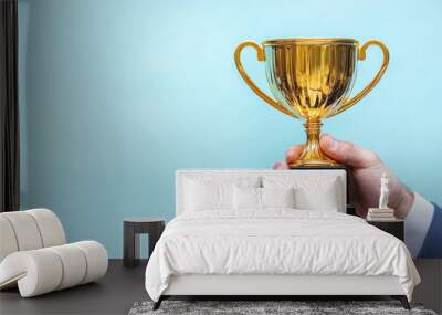 Businessman or boss holding champion golden trophy for winner, success and achievement award in business concept. Man in a suit with a gold trophy prize on blue background. Wall mural