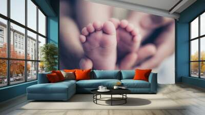 Feet of a newborn baby in the hands of parents. Happy Family oncept. Mum and Dad hug their baby's legs. Wall mural