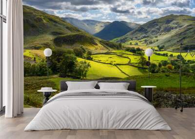 Two walkers on Lake District hillside overlooking a sunlight valley Wall mural