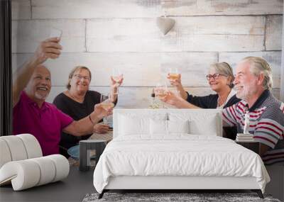 4 senior people two man and two women taking selfie at the table at home during a lunchh together. friendship concept for elderly people. hearth on the wall Wall mural