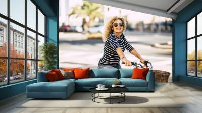 Beautiful and cheerful adult young woman enjoy bike ride in sunny urban outdoor leisure activity in the city - happy people portrait - trendy female outside having fun Wall mural