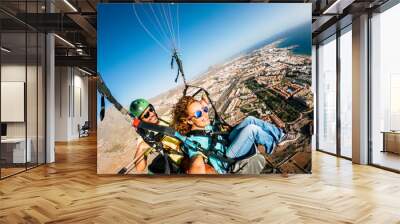 Cheerful happy woman to paraglyde experience with pilot - couple having fun in the air paraglyding over the city with coastline view - tourist and summer holiday vacation active people Wall mural