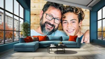 Cheerful people portrait with father and son hug and laughing a lot together having fun and looking at the camera - wooden background and joyful generations concept-handsome young and old males Wall mural