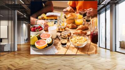 Close up of group of unrecognizable people eating brekfast all together on a wooden table under the sun -outdoor food activity and vacation family concept - fruit coffee and brioches Wall mural