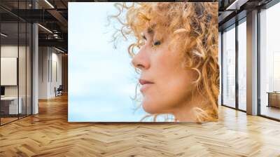 Close up side portrait of pretty adult woman with closed eyes and blonde natural healthy curly long hair. Concept of thinking and interior balance. Daydreamer outdoor female people enjoying nature Wall mural