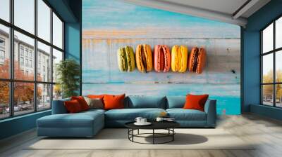 Coloured macarones biscuits on a blue wooden table background - concept of bakery and party lifestyle with sweet snacks - food decorations viewed from above with creak and chocolate Wall mural