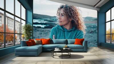 Concept of young woman and emotions. Inner balanced portrait of female enjoying freedom and sensations outdoor. Travel and wanderlust lifestyle people. Beautiul lady with curly long hair smiling Wall mural