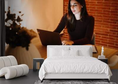 Cute and professional woman working serenely and smiling in the evening at her home office. She relaxes while enjoying her business on the laptop, embracing freelance life and modern remote working Wall mural