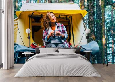 Freedom and alternative camping oslution with roof tent on the car. One adventure woman enjoy alternative vacation alone sitting outside her tent in the forest woods. Freedom and journey lifestyle Wall mural