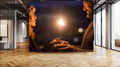 Happy couple celebrate together with love and romance in the new year eve night firing sparklers. Man and woman enjoy magic moment relationship. Mature people aging forever married concept lifestyle Wall mural