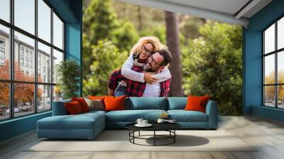 Happy couple of adult people caucasian man and woman have fun together in outdoor leisure activity in the nature- environment and love or forest concept with playful and youthful hipsters traveler Wall mural