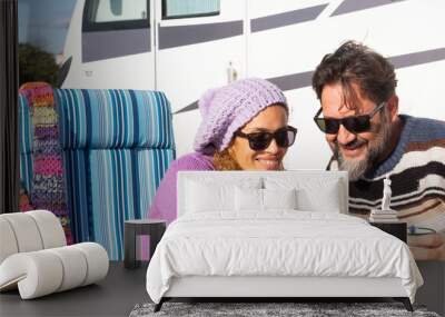 Happy couple of van camper tourist traveler enjoy time together using mobile phone to plan road trip and next destination. People and vehicle vacation lifestyle. Sitting outside at the table. Vehicle Wall mural