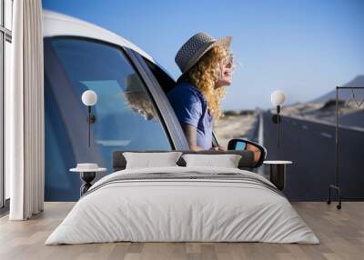 Happy freedom concept with beautiful lonely traveler adult caucasian woman enjoy the trip lifestyle outside the window of her white car - transport and long asphalt road in background Wall mural