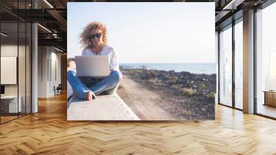 Happy lifestyle digital nomad young cheerful woman work outdoor with laptop computer - people and modern technology job and communication related - alternative office at the beach Wall mural