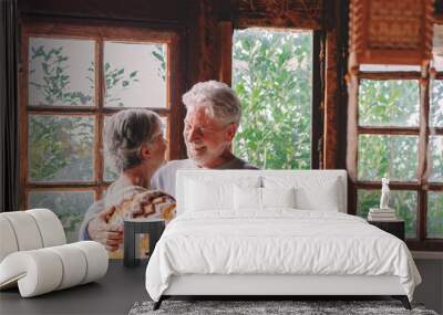 Happy senior couple smile and dance at home enjoying love and relationship together. Active old man and woman have fun in indoor leisure activity. Nature woods view from windows Wall mural