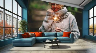 Happy woman celebrating outdoor with sparkler fire and smile. Concept of people and celebration. Birthday and new year eve. One female alone enjoy life in autumn. Green background nature Wall mural