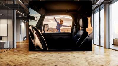 Happy woman in travel adventure lifestyle summer vacation jump with hoyful and smile outside the car viewed from inside through the door - concept of road trip and female driver - freedom journey life Wall mural