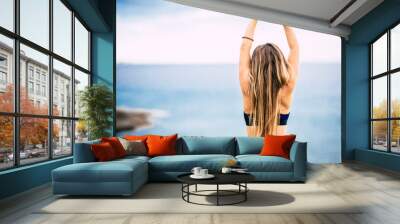 Healthy lifestyle people concept with beautiful long blonde hair girl viewed from back do some stretching in front of the ocean view outdoor - fit woman and attractive female Wall mural