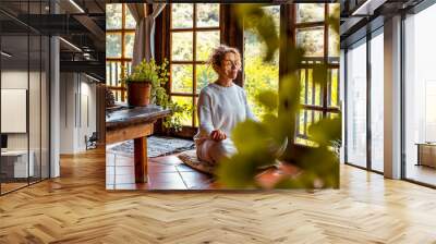 Interior balance and love for yourself concept lifestyle. One middle age youthful woman doing meditation in yoga asana position at home sitting on the floor. Healthy natural exercise. Mental wellbeing Wall mural