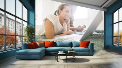 nice caucasian young attractive couple stay lay down on the bed working with laptop and mobile phone internet connected. indoor home leisure activity on the bedroom. happy lifestyle concept Wall mural