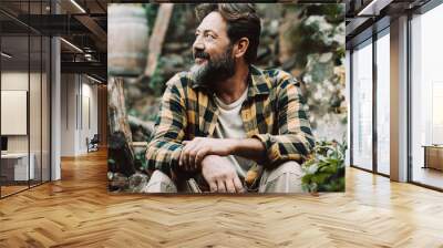 One happy and serene adult man sitting outdoor in the green nature garden. Copy space image of alternative male people having relax time alone enjoying silence and loneliness. Lifestyle concept Wall mural