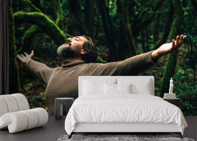 One man outstretching arms in the green dark forest. Environment and travel destination concept lifestyle. People in outdoors leisure activity enjoying breathing in the woods. Climate change warming Wall mural