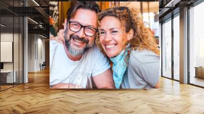 Portrait of happy adult couple posing for a picture sitting at the table restaurant in outdoor. Tourist having lunch on summer holiday vacation outdoor leisure activity together. Cheerful people smile Wall mural