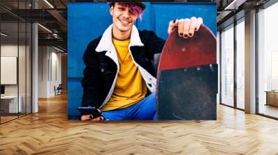 Portrait of happy and cheerful young alternative teenager boy with skateboard and cellular phone - diversity people concept and youthful lifestyle - blue home door in background - people  smile Wall mural